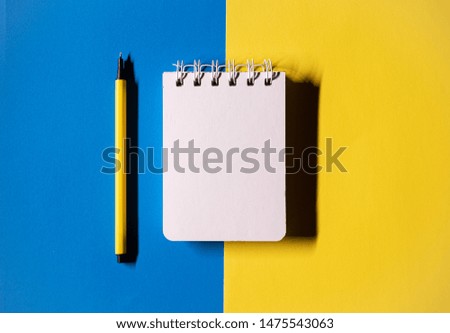 Flat lay style picture of workspace with office supplies on colored blue and yellow background. Top view