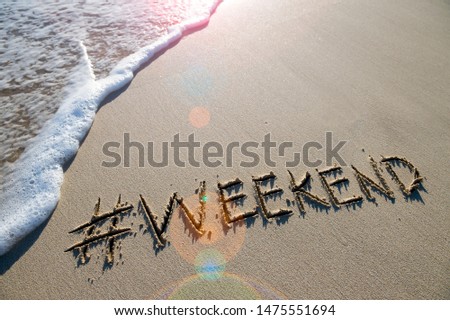 Modern travel message for the beach with a social media-friendly hashtag written with the word "weekend" in smooth sand with incoming wave