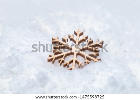 Wooden snowflake toy on snow with empty space. Concept for New Year or Merry Christmas. Holiday winter background.