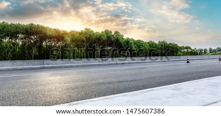 Asphalt highway and green forest with beautiful clouds landscape at sunset