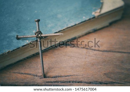 close up nail cross and book on old wood table, religion and life, happy halloween day concept, vintage tone
