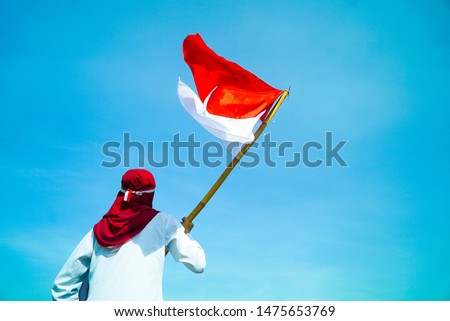 Asian Hijab flapper Indonesian flag with clear blue sky background, Indonesia independence day