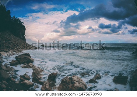 Rocky seashore. Strong waves and wind. Storm. Ocean against the background of the cloudy sky. Big stones on the seashore.