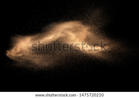 Brown colored sand splash against dark background. Dry river sand explosion isolated on black background. Abstract sand cloud.