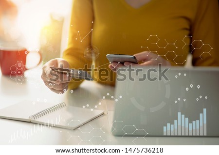 Businesswoman holding credit card and using smartphone with laptop computer. Online shopping concept . Finance task. Digital tablet with virtual icon diagram.