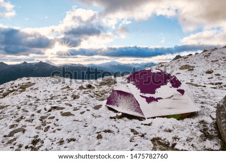 Purple tent under snow in the mountains. Trekking mountain camp concept