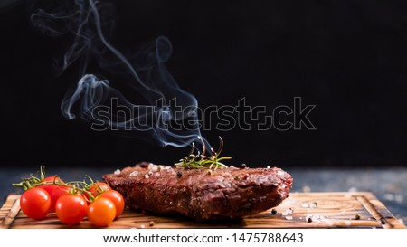 Steakhouse menu. Striploin steak. Grilled beef meat with cherry tomatoes and burning rosemary twig. Royalty-Free Stock Photo #1475788643