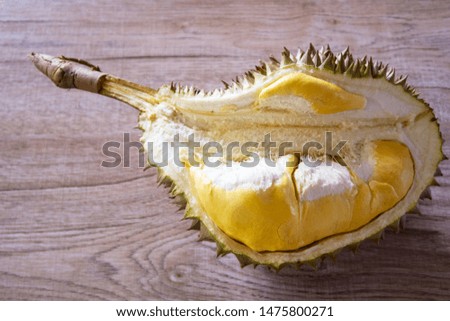 Durian, King of fruits on wooden table background, copy space for text. Tropical summer fruit concept with golden-yellow color of peeled ripe durian with green thorn  bark, popular in Thailand & Asia