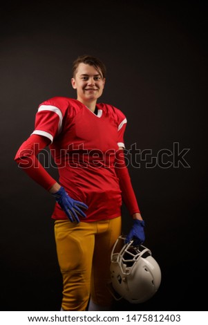 Picture of happy american brunette soccer player with helmet in her hand at empty black background