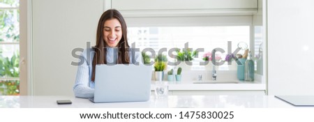Wide angle picture of beautiful young woman working or studying using laptop with a happy face standing and smiling with a confident smile showing teeth Royalty-Free Stock Photo #1475830025