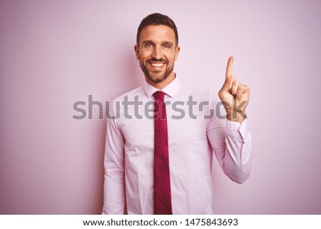 Business man wearing tie and elegant shirt over pink isolated background with a big smile on face, pointing with hand and finger to the side looking at the camera.