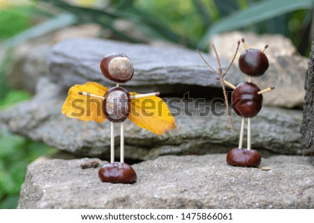 Angel and devil figures made from chestnuts and safety matches and dry leaves in the autumn garden
