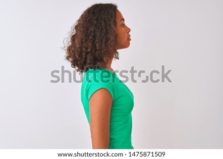 Young brazilian woman wearing green t-shirt standing over isolated white background looking to side, relax profile pose with natural face with confident smile.