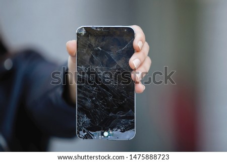Broken glass screen smartphone in hand of upset gir
