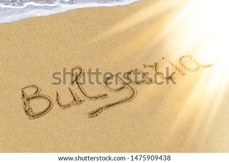 Bulgaria title on the light sand beach near the black sea coast. Brilliant sun ray falls on the letters.