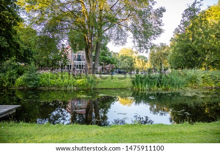 House in a city park, Rotterdam, Netherlands. Trees shadows, reflections on the pond, sunny spring day