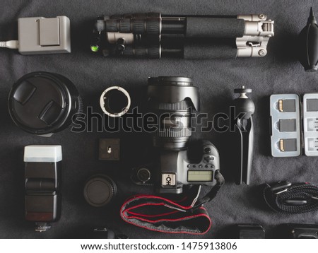 top view of work space photographer with digital camera, flash, cleaning kit, memory card, tripod and camera accessory on black table background