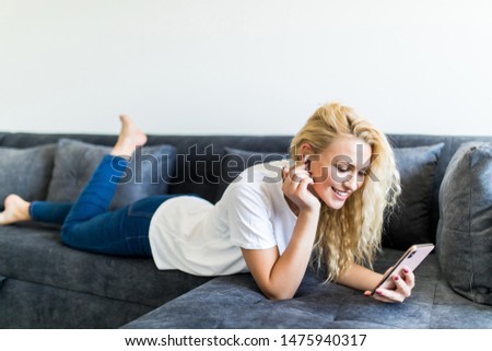 Picture of happy adult woman using phone at home in the living room