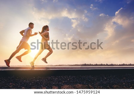Young couples running sprinting on road. Fit runner fitness runner during outdoor workout with sunset background Royalty-Free Stock Photo #1475959124