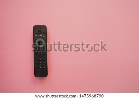 Watching a movie at home, concept on a pink background, copy the space to the right. TV remote