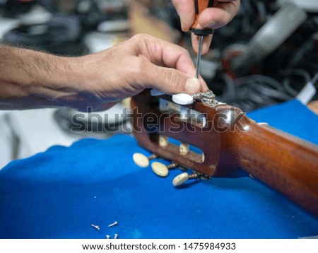 pair of male hands fixing a guitar