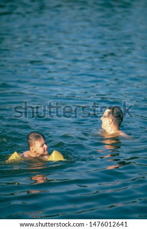 father with kid having fun in water swimming together summer vacation