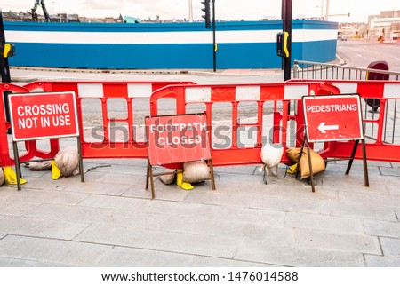 Footpath and pedestrian crossing closed with red barriers because of construction site in a city centre