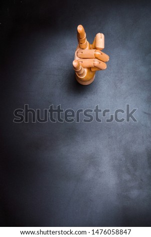 Wooden hand indicating on a dark background, where to write a text