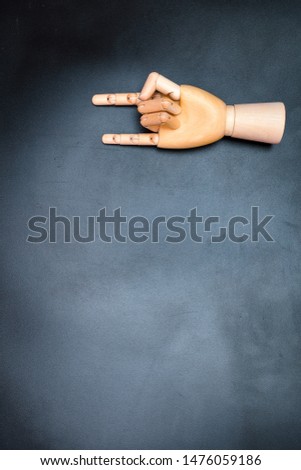 Wooden hand that makes horns, on a dark background, where you can write a text