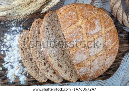 Round loaf of bread the whole bread on wooden background. above view.