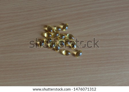 Fish oil capsules with omega 3 and vitamin D on wooden texture. 