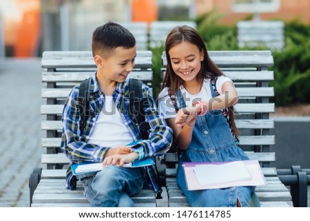 Happy child sit on bench, playing with smart watch with  smile. Learning new technology together. Lifestyle. Royalty-Free Stock Photo #1476114785