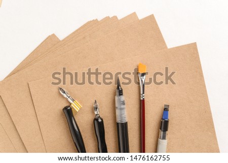 Calligraphy concept, accessories and tools for handwriting,ink, brush,writing training,blank sheets of white paper and cardboard crafting on wooden table,Top view