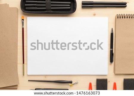 Calligraphy concept, accessories and tools for beautiful handwriting,pencils,pens, ink, brush, ,sponge, writing training,blank sheets of white paper and cardboard crafting on wooden table
