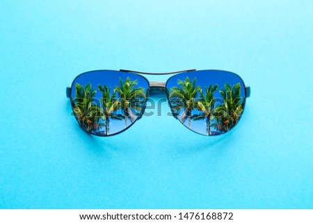 Summer vacation concept. Sunglasses with palms and blue sky on blue background.