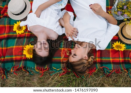 Top view of happy woman smiling and playing with her cute little child, lying outdoor.Loving mother and daughter spend time together in a park. Mom and kid has fun. Mother's day