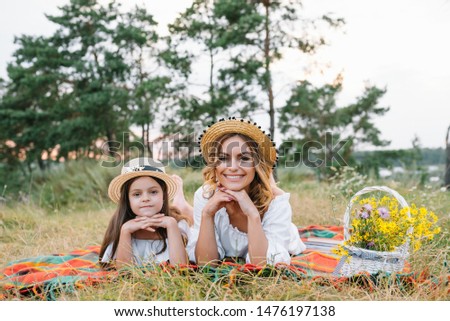 happy woman smiling and playing with her cute little child, lying outdoor.Loving mother and daughter spend time together in a park. Mom and kid has fun. Mother's day