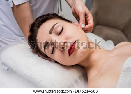 Beautiful young woman enjoying head massage in spa salon. Cosmetology concept