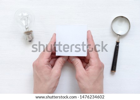 Ideas list mockup. In search of inspiration. Blank stickers on a businessman hand over a white wooden background.