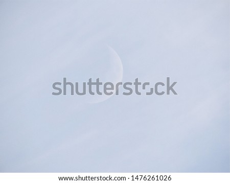 Pale blue sky with pale white crescent moon in summer evening can be used as background or backdrop with space for text 