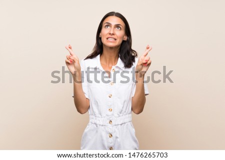 Young woman over isolated background with fingers crossing and wishing the best