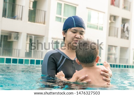 Mother teaching infant 9 month baby boy swimming in pool, Mom with son