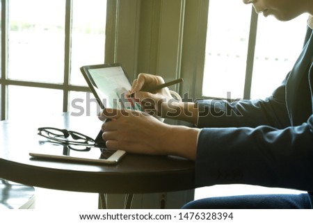 businessman using  drawing comment in tablet for analysis graph visualization at coffee shop