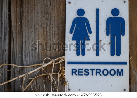 female and male restroom bathroom sign at the wooden door with grass around 
