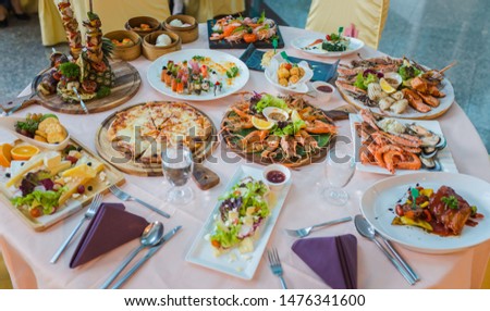 Picture of dinner table set with variety food, seafood, sushi, sashimi, pizza, barbeque, cheese and salad