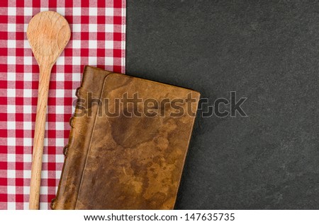 Wooden spoon and coockbook on a slate plate 