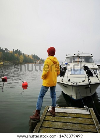 Man Yacht Autumn. Thoughtful man traveler on an old wooden pier  looking at the sea. Autumn picture of a man traveler near to yacht. Jetty. Scandinavia:  Islands Mists Fog Fall season Relax Hugge.