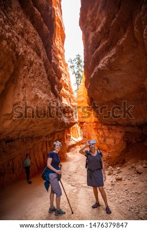 Two adult women hiking and taking pictures in Bryce Canyon National Park, Utah, USA while on vacation. Candid photo