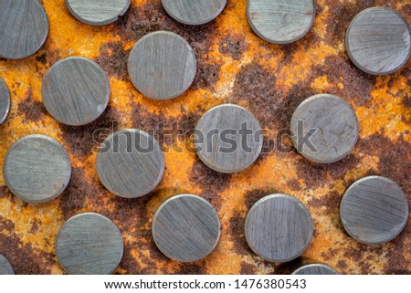 set of small round ceramic ferrite magnets - top view against rusty metal sheet Royalty-Free Stock Photo #1476380543