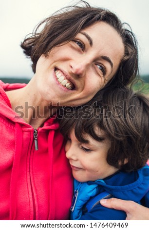 The boy hugs mom. Woman rests with her son in nature. The child kisses mom. Portrait of a mother and baby.